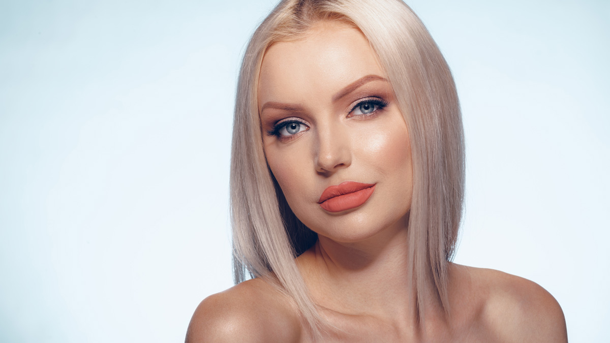 Woman with a chic, chin-length blunt box bob hairstyle and bouncy internal texture.