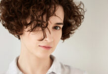 Cropped Curls: Your Complete Guide to Short Curly Haircuts Beautiful woman highlighting a bouncy short hairstyle with perfectly hydrated cropped curls.