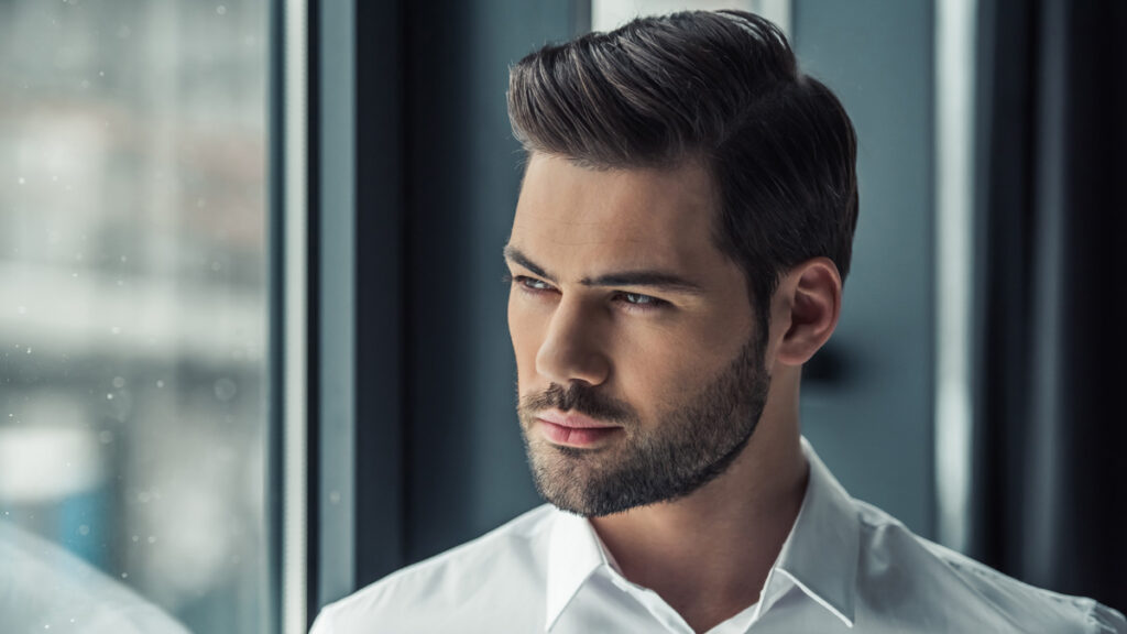 Handsome male model with thick dark ash brown hair featuring a precision skin fade and textured modern volume.