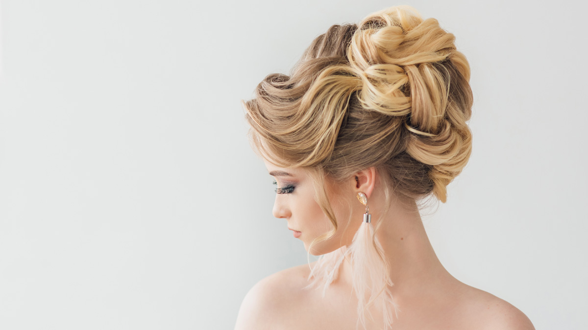 Close up of a highly structured and romantic updo wedding hairstyle with soft tendrils.