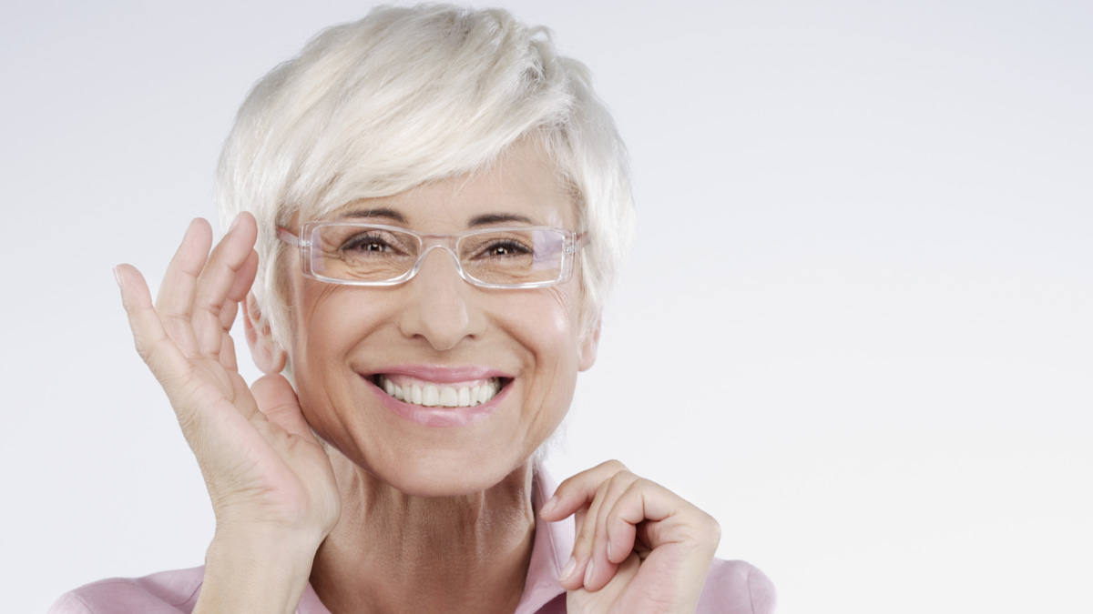 A bright close-up of a cheerful senior woman wearing a neo-shixie haircut.