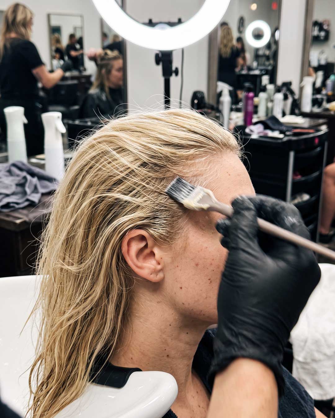 Stylist executing the rapid basin lightening technique on the delicate blonde hairline